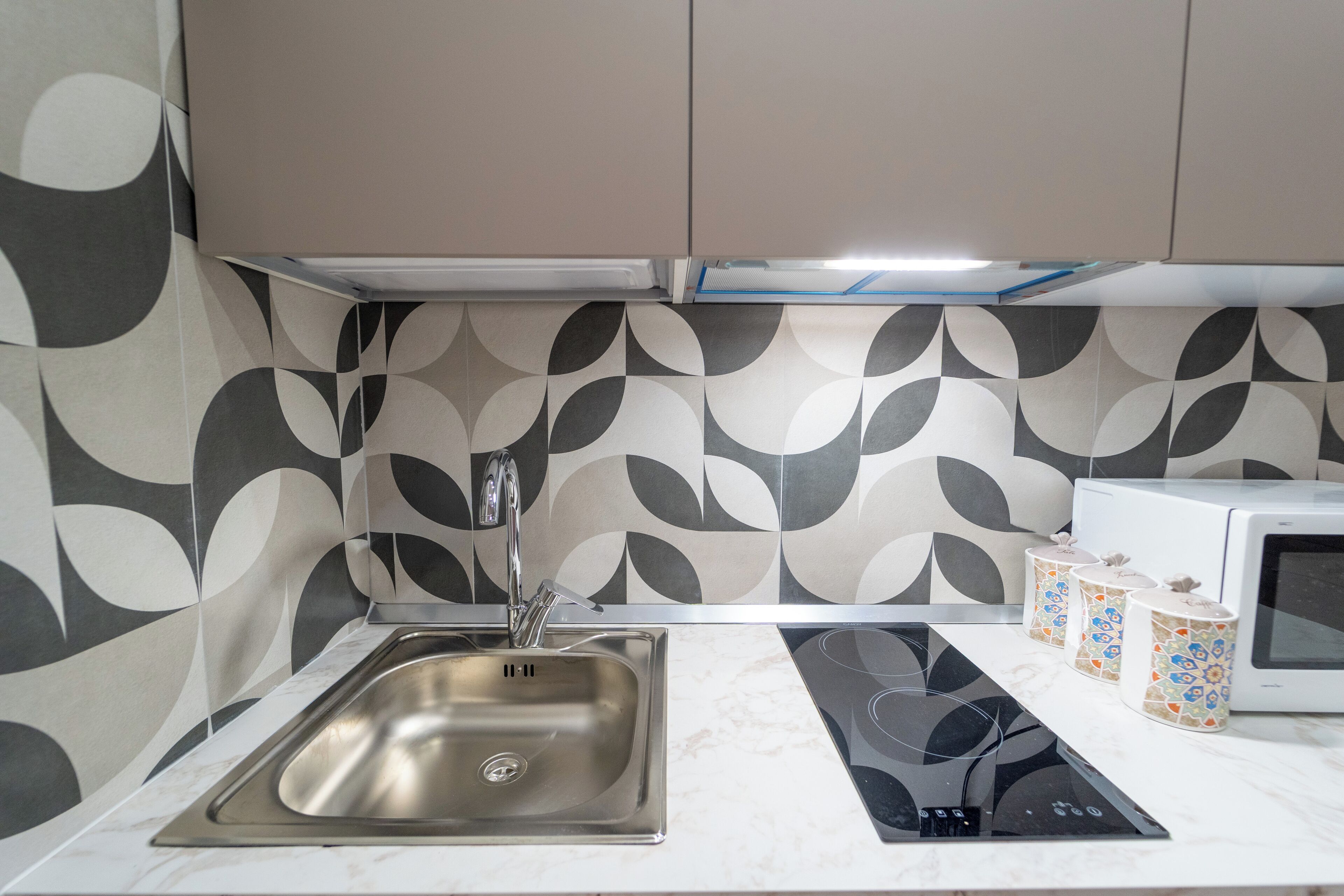 A kitchen with a stainless steel sink, a microwave, and a stovetop.
