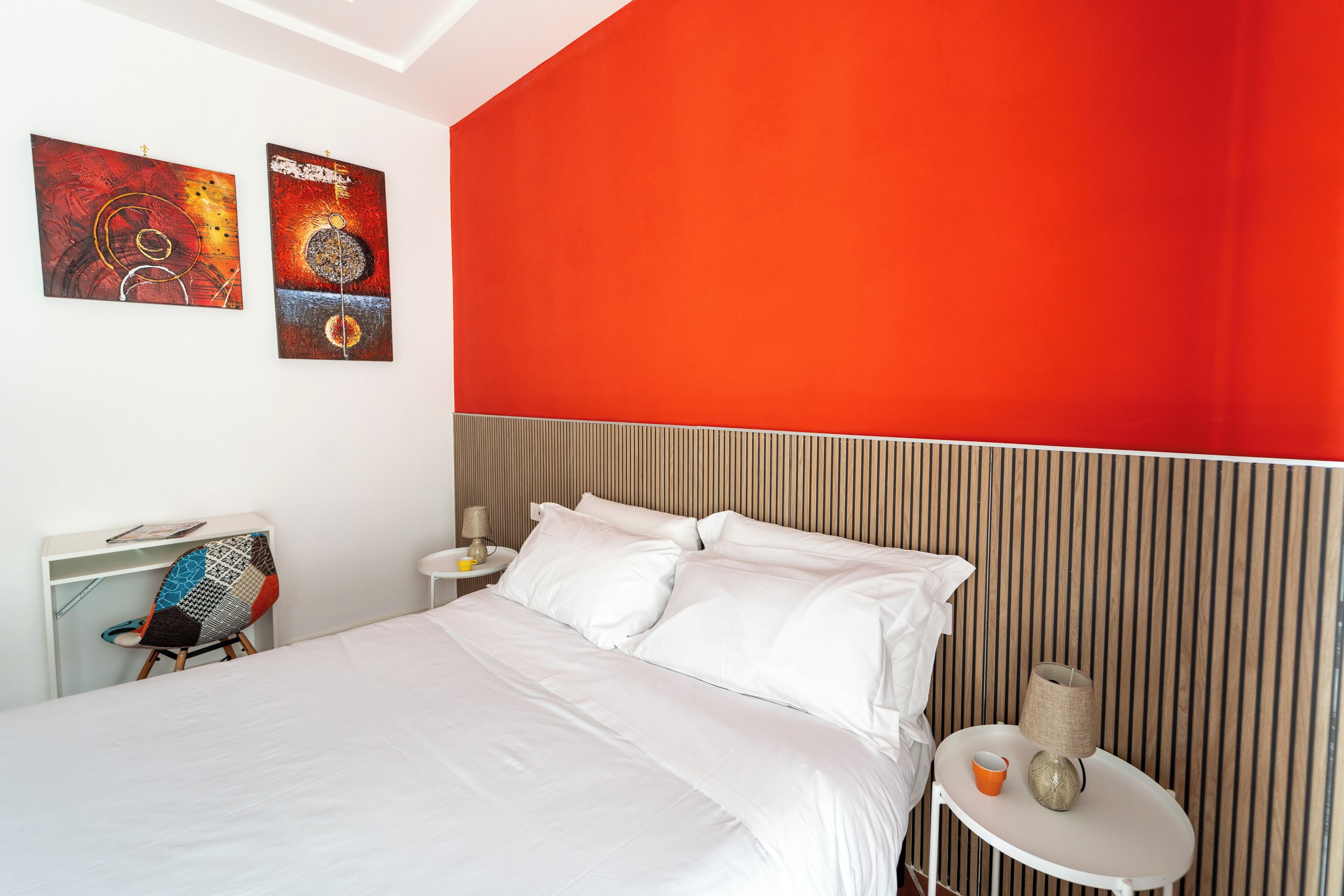 A hotel room with a large bed, a nightstand, a chair, and two wall art pieces.