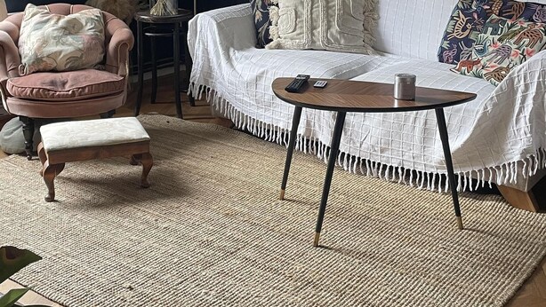 Ett mysigt vardagsrum med en mörkblå vägg, en vit soffa, ett runt soffbord och en mönstrad matta.