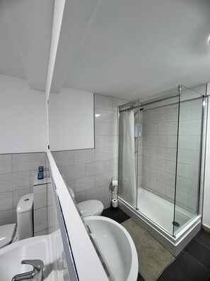 Un baño moderno con ducha acristalada, lavabo blanco y retrete.