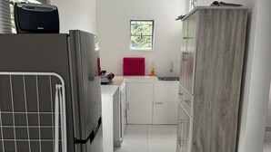 Una cucina moderna con mobili bianchi, un piano di lavoro rosa e una finestra con vista sul verde.