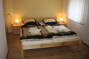 A wooden bed with a white mattress and a patterned blanket. There are two bedside tables with lamps. - Kalkwerk Vacation Rental (Thum)