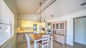 A kitchen with a wooden dining table and chairs, white cabinets, and a built-in oven.