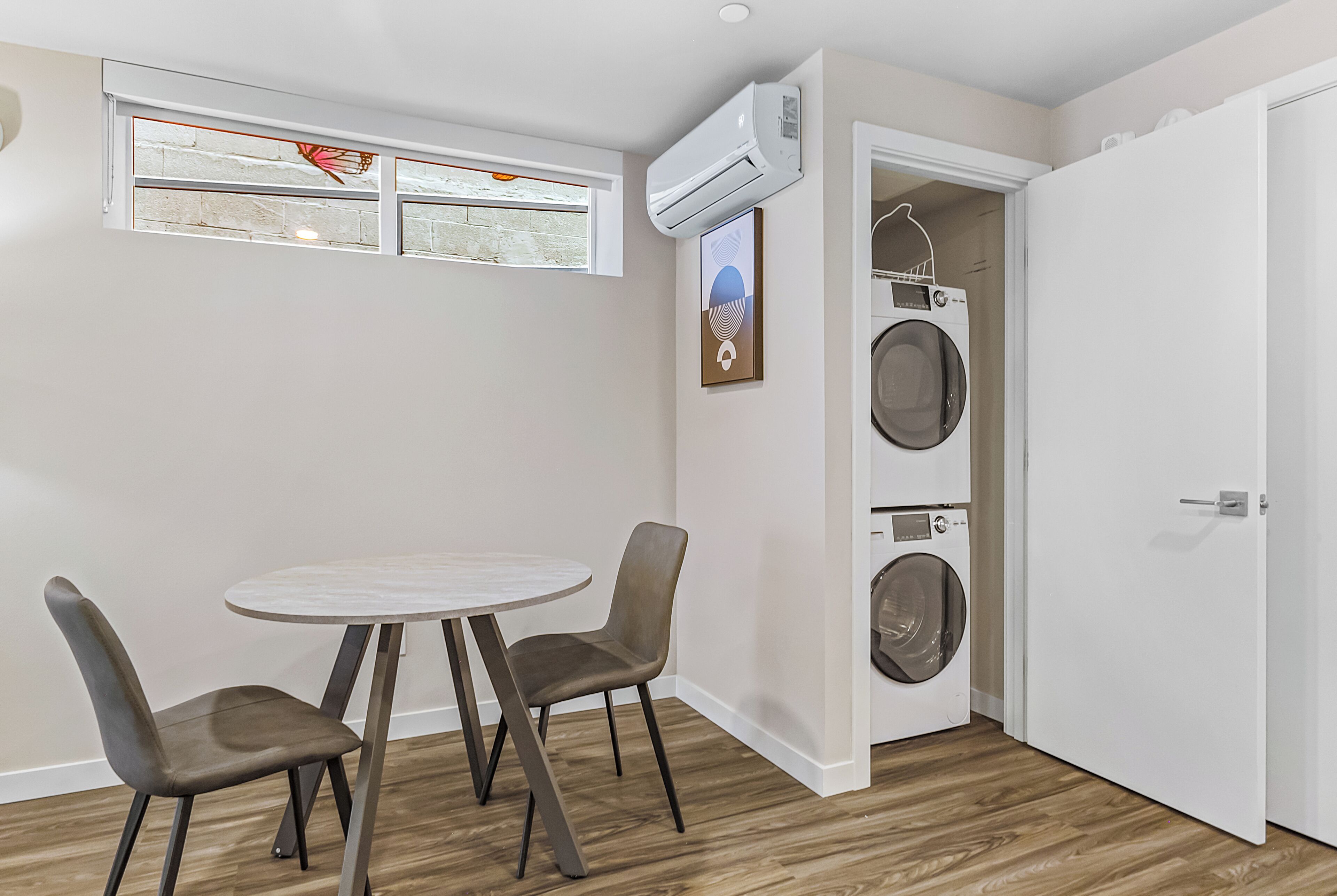 A compact living space with a dining area, a washing machine, and a door leading to another room.