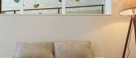 A living room with a beige sofa, a glass coffee table, and a floor lamp.