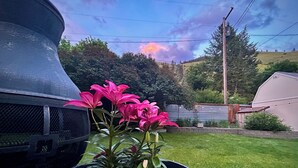 Un jardín con una planta en maceta de flores rosadas y un césped verde.