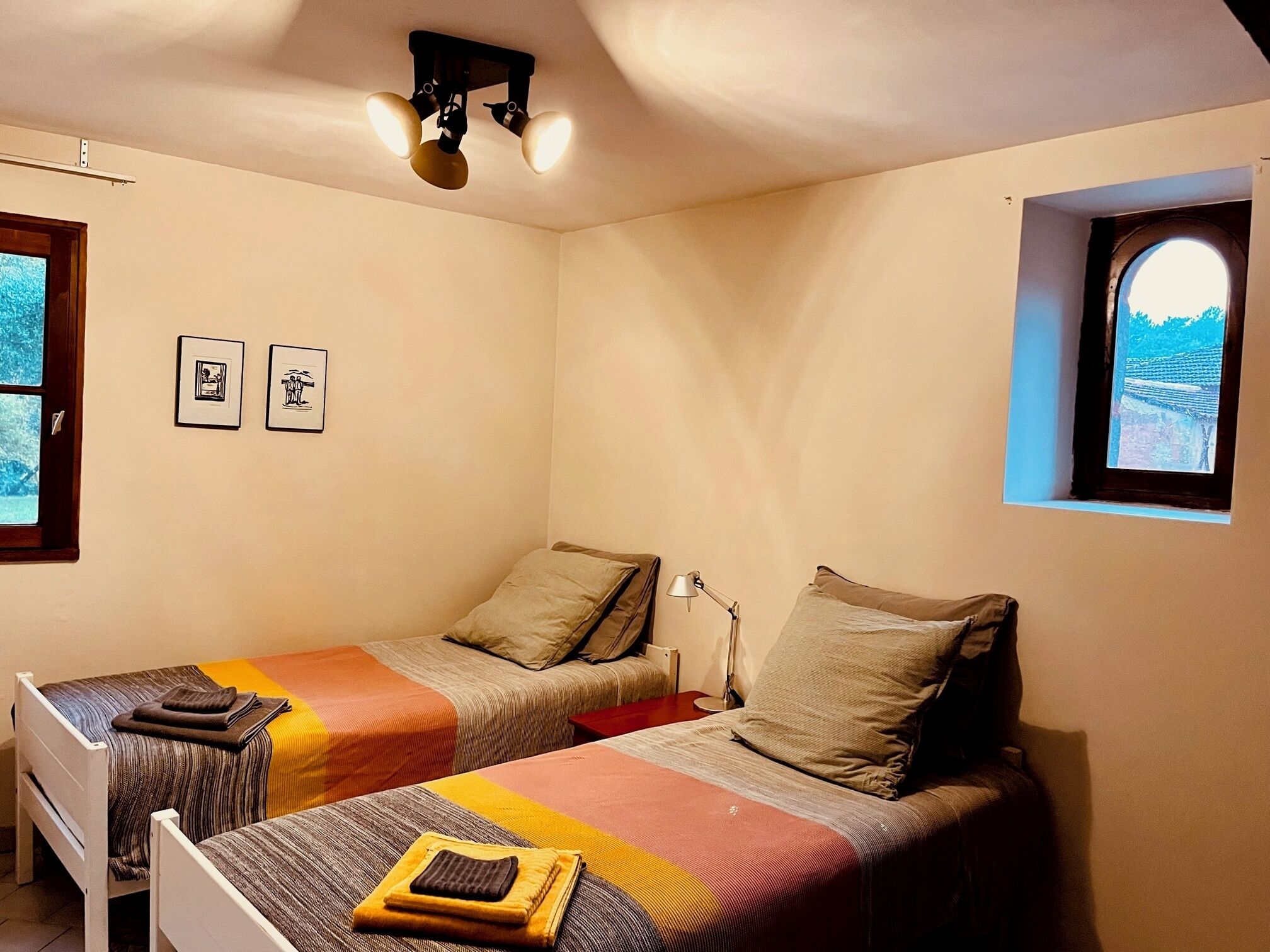 A small, cozy room with two single beds, a desk, and a window with a view.