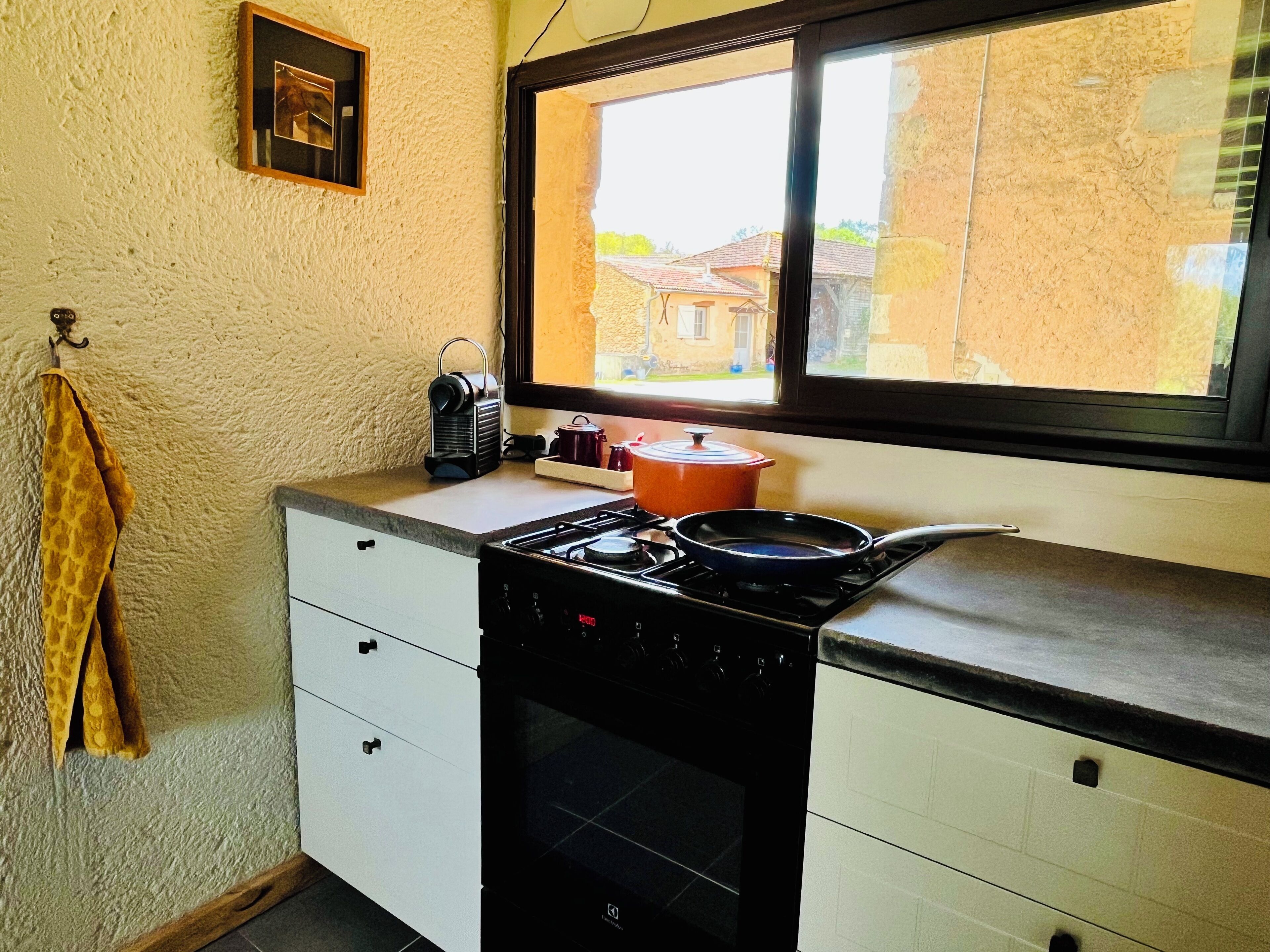 A compact kitchen with a stove, oven, and a window overlooking a residential area.