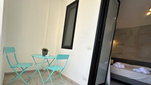 A small room with a bed, a table, and two chairs. - Marilu Vacanze (Bari)