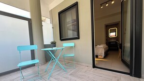 A small balcony with turquoise metal chairs and a table, a potted plant, and a view of a bedroom with a bed and a mirror. - Marilu Vacanze (Bari)