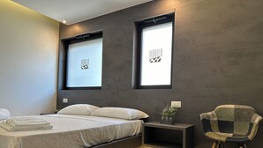 A modern bedroom with a bed, bedside tables, and a chair. - Marilu Vacanze (Bari)