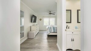 A bedroom with a bed, a dresser, a vanity with a mirror, and a ceiling fan. - Luxury 2BR Shipyard Villa: Golf Views, Heated Spa & Walk to Beach (Hilton Head Island)