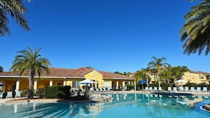 Ein Resort mit großem Pool, gelben Gebäuden und Palmen.