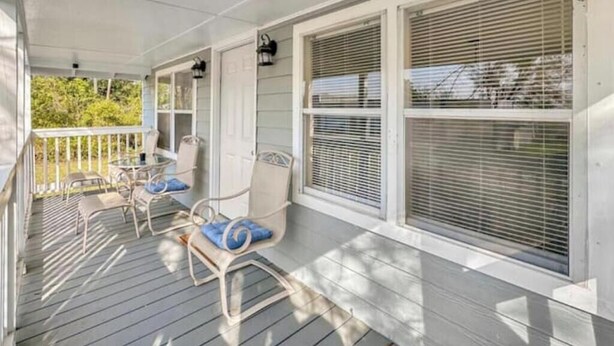 A porch with a table and chairs, a door, and windows with blinds. - Great Vacation Escape (Savannah)