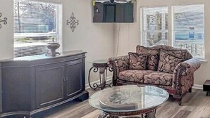 A living room with a sofa, a glass coffee table, a patterned rug, and a cabinet. - Great Vacation Escape (Savannah)