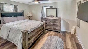 A bedroom with a bed, dresser, vanity, and ceiling fan. - Great Vacation Escape (Savannah)