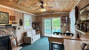 A rustic cabin interior with a stone fireplace, wooden ceiling, and a cozy seating area. - Bay Loft Couples Retreat – Nature, Comfort & Charm (Stevens Point)