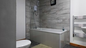 Kylpyhuone, jossa on valkoinen kylpyamme, suihku ja wc.