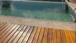 A rooftop pool with clear water, surrounded by buildings and a clear sky.