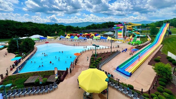 A water park with a large pool, multiple slides, and umbrellas.