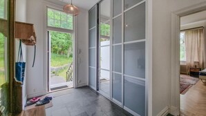 Ein geräumiger Flur mit einem großen Schiebeglasfenster zum Garten, einer hölzernen Bank und einer Pendelleuchte.
