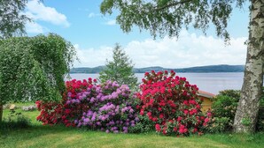 Ein Garten mit blühenden Sträuchern und Seeblick.