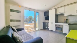 A modern apartment with a living area, kitchen, and sliding glass doors to a balcony. - Seafront apartment 4 people - 2 Pools (Saint-Raphaël)