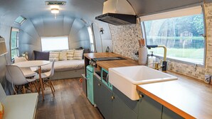 A compact kitchen with a sink, stove, and window overlooking a garden.