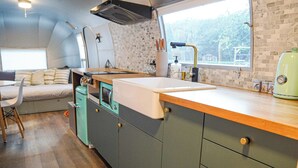A compact kitchen with a wooden countertop, a sink, and a window providing a view of the outdoors.
