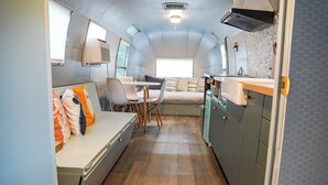 A compact interior with a bed, a dining area, and a kitchenette.