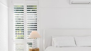 A white room with a bed, a wooden nightstand, a lamp, and a window with blinds. - The Bower, Byron Hinterland. Farm stay in Teven, Australia (Teven)