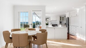 Een moderne keuken met witte kasten, een centraal eiland en een eethoek met een tafel en stoelen.