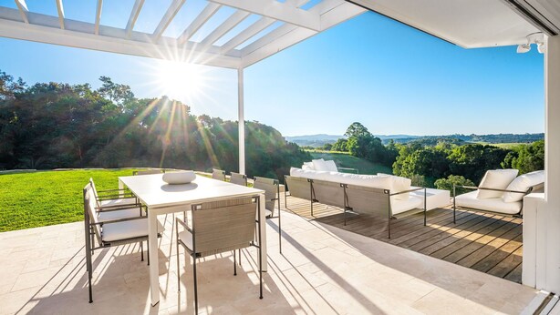 Een terras buiten met een tafel en stoelen, een bank, en een pergola.