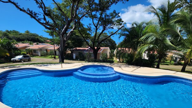 A swimming pool with a curved edge, surrounded by a concrete deck. - Casa Mandarina Junge Villa 3 pools (Veintisiete de Abril)
