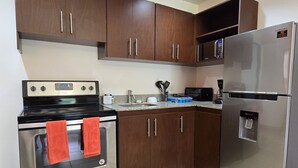 A kitchen with a stainless steel refrigerator, a black stove, and wooden cabinets. - Casa Mandarina Junge Villa 3 pools (Veintisiete de Abril)