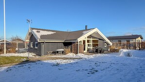 Ein zweistöckiges Haus mit Garage, überdachter Terrasse und einem schneebedeckten Garten.