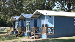 A row of blue cabins with wooden stairs and railings, each with a window and a door.