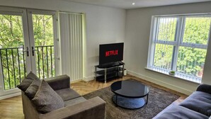 A modern living room with a flat-screen TV, grey sofas, and a glass coffee table. - Spacious City Living / Free Parking (Birmingham)