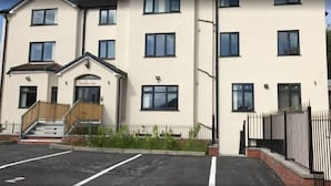 A multi-story building with a flat facade, a front entrance with steps, and a parking area in front. - The No.10  (Manchester)
