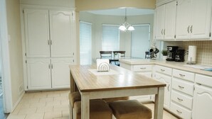 A kitchen with white cabinets, a wooden table, and a bench. - Large 4-bd 3 bath home + bonus room. Dogs are welcome. Sleeps 16+ (Abilene)
