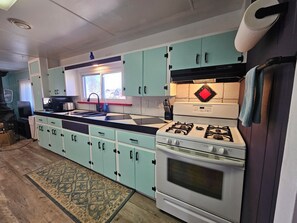 Una cocina con armarios azul claro, estufa y pileta.