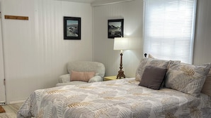 A bedroom with a bed, a nightstand, a lamp, and two framed pictures on the wall.