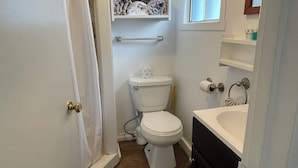 A compact bathroom with a toilet, a sink, and a window.