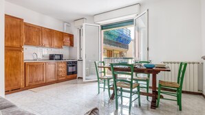 Een kleine keuken met houten kastjes en een eethoek met groene stoelen.