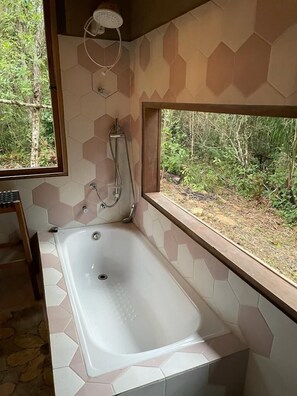 A bathroom with a large bathtub, a shower, and a window with a view of the outdoors. - Vila Dravida (Iporanga)