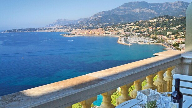 Un paysage urbain côtier offrant une vue dégagée sur la mer et les montagnes en arrière-plan.