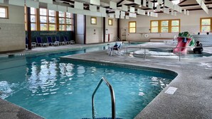 Una piscina interior con agua cristalina, un trampolín y un tobogán.