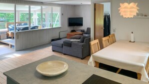 A modern living room with a sofa, a television, a dining table, and a large window. - Amazing home in Ebeltoft with WiFi (Ebeltoft)
