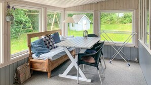 A cozy room with a wooden bed, a table, and chairs, large windows, and a view of greenery outside. - Amazing home in Ebeltoft with WiFi (Ebeltoft)