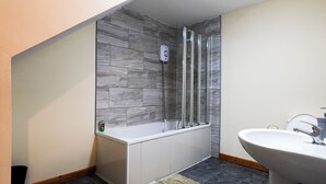 Une salle de bain avec une douche, une baignoire et un lavabo.